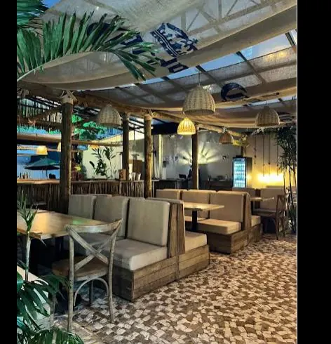 Ambiente interno do Caraíva Bar com madeira e luminárias de palha