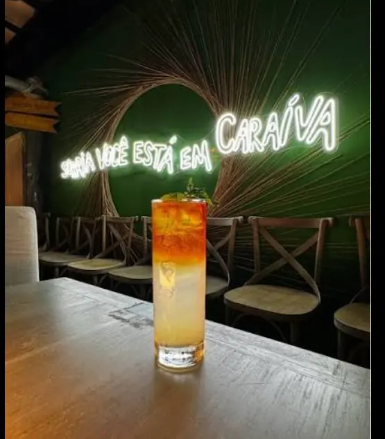Drink diante do neon Você só não está em Caraíva